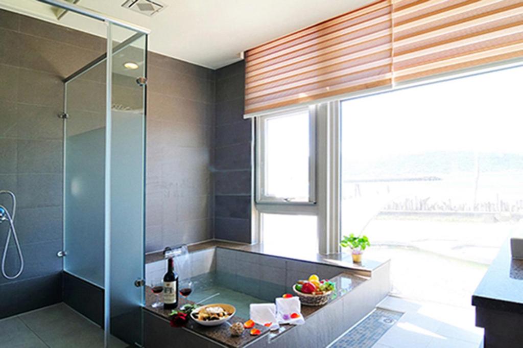 a bathroom with a shower and a sink and a window at JinShan Sakura Bay Hot Spring Hotel in Jinshan