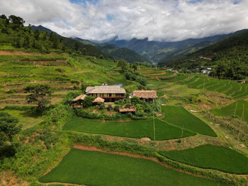 an aerial view of a house on a green field at Zoni Home Trạm Tấu in Cham Ta Lao