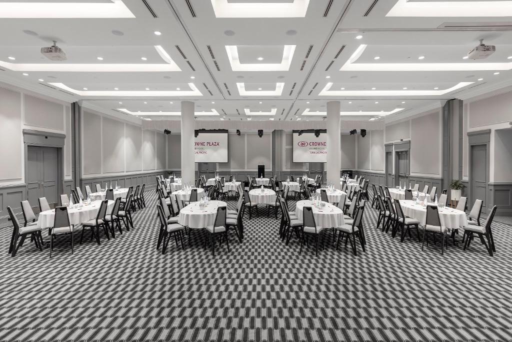 uma sala de jantar com mesas e cadeiras num edifício em Crowne Plaza Terrigal Pacific, an IHG Hotel em Terrigal