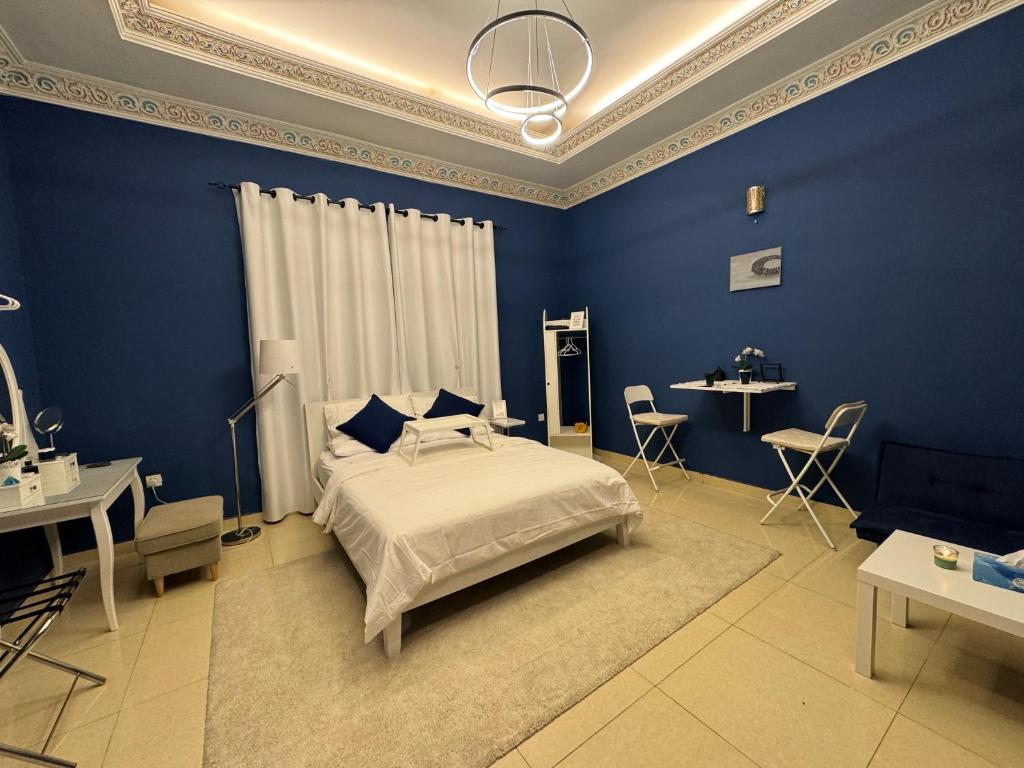 1 dormitorio con paredes azules, 1 cama y mesas en Private room in the heart of Dubai with Burj Khalifa view, en Dubái