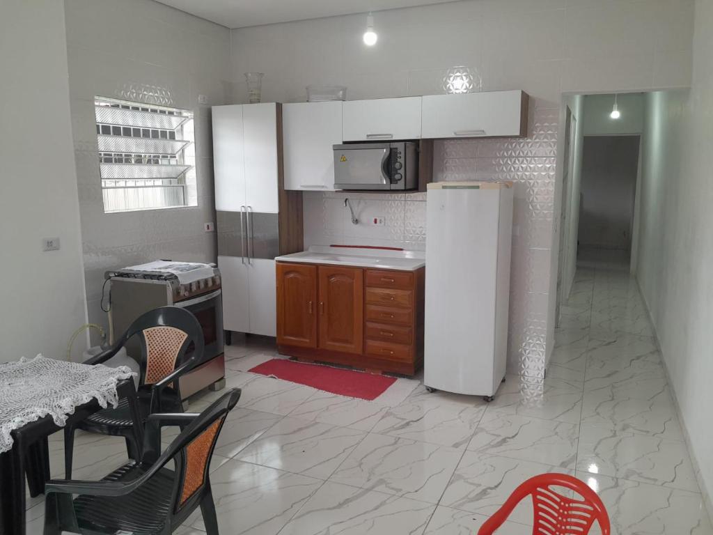 een keuken met een koelkast en een tafel en stoelen bij Casa do Enzo in Peruíbe