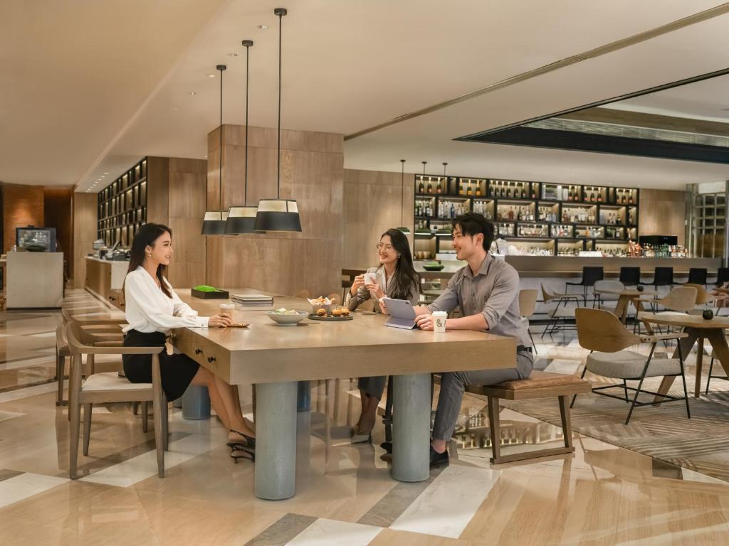 three people sitting at a table in a restaurant at Sheraton Guangzhou Hotel in Guangzhou