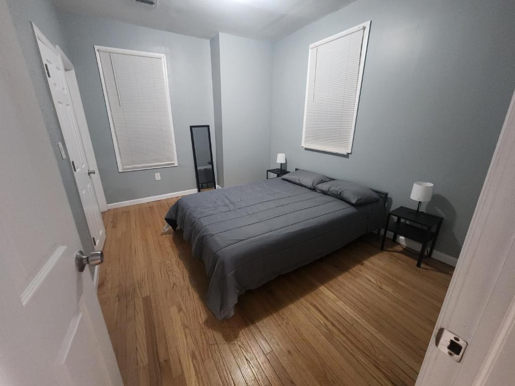 a bedroom with a bed and two windows at Mins to NYC, Cosy 3 Bedroom Apartment in Jersey City