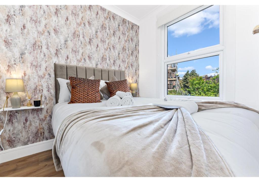 a bedroom with a large bed with a window at Energizing Getaway: Newly Renovated 2 BR Flat in London