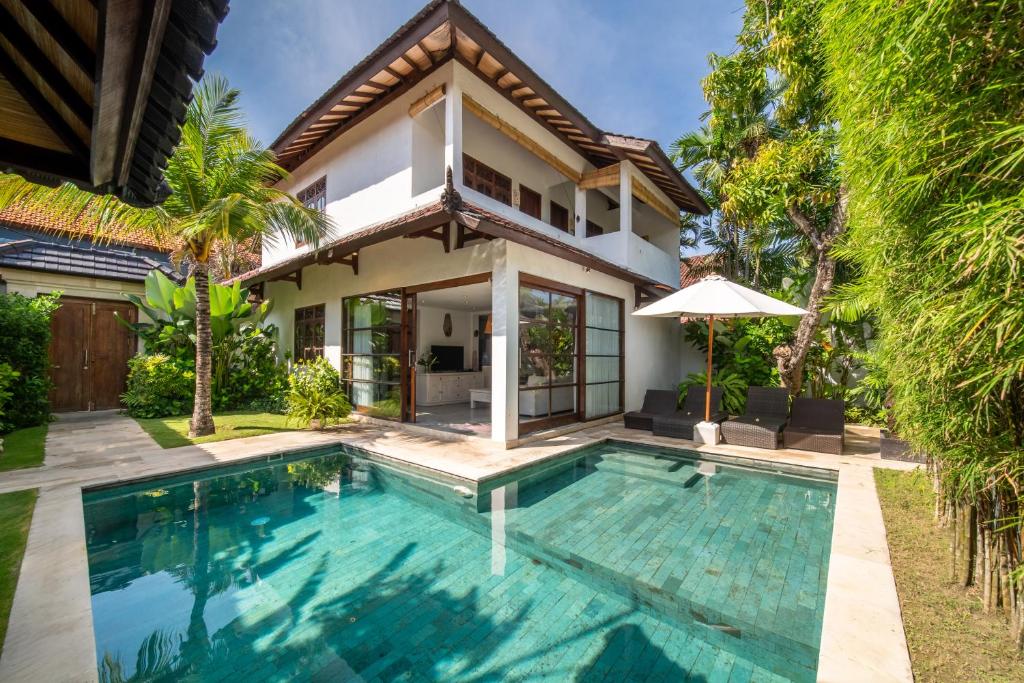 a villa with a swimming pool in front of a house at Villa Bewa in Seminyak