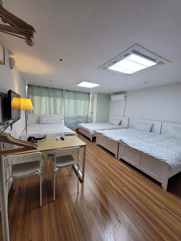 a room with three beds and a desk and a table at White Stay in Seoul