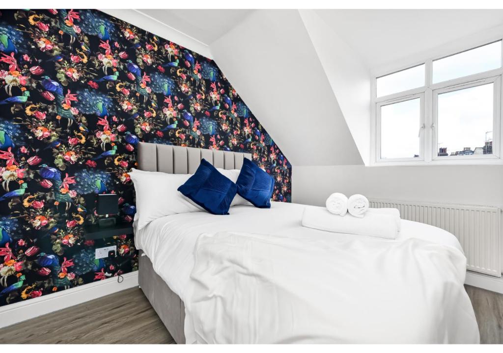 a bedroom with a large bed with a floral wallpaper at Awesome Loft Flat - Seconds to London’s Best Park! in London