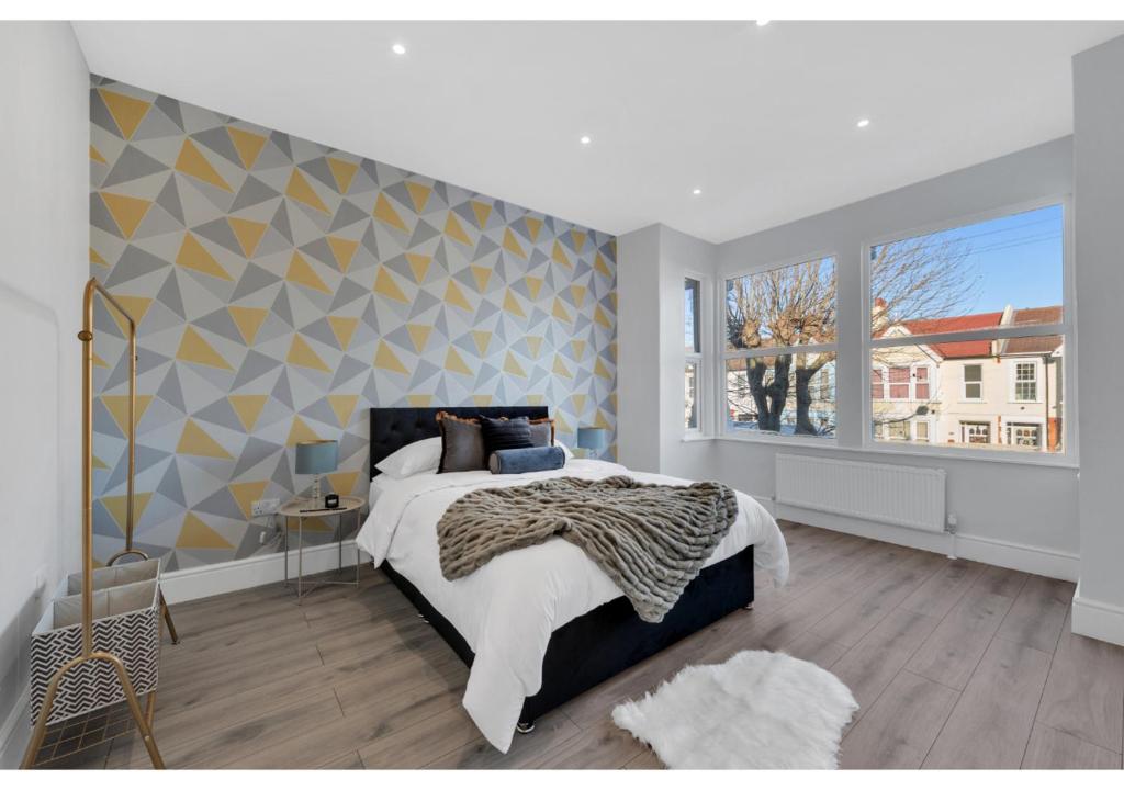 ein Schlafzimmer mit einem großen Bett und einem großen Fenster in der Unterkunft Astonishing 4BR House - Perfect for a Big Family in Southend-on-Sea