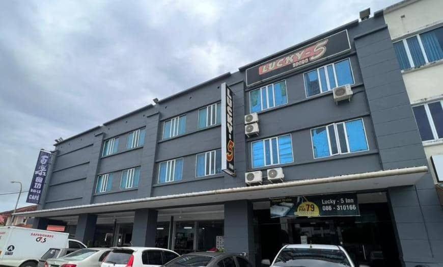 a building with cars parked in front of it at LUCKY - 5 INN in Bintulu