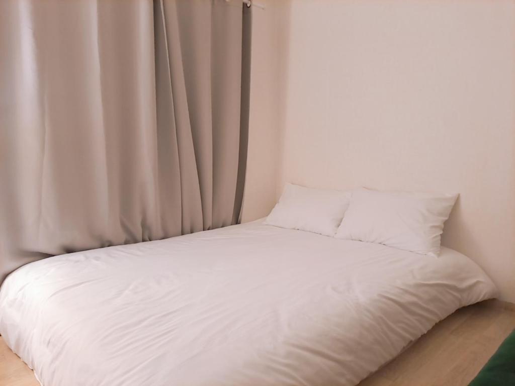 a bed with white sheets and pillows next to a window at Stay Cheongnyang in Seoul