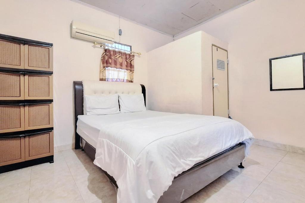 una camera da letto con un letto con lenzuola bianche e una finestra di Handira Homestay Syariah Padang RedPartner a Duku