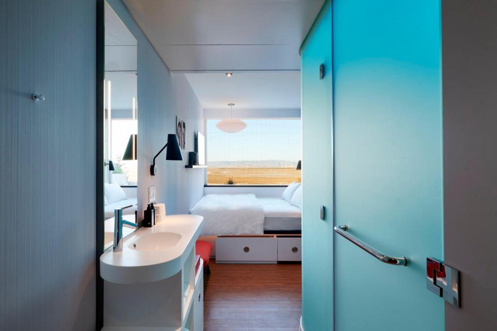 a bathroom with a sink and a bed and a mirror at citizenM Menlo Park in Menlo Park