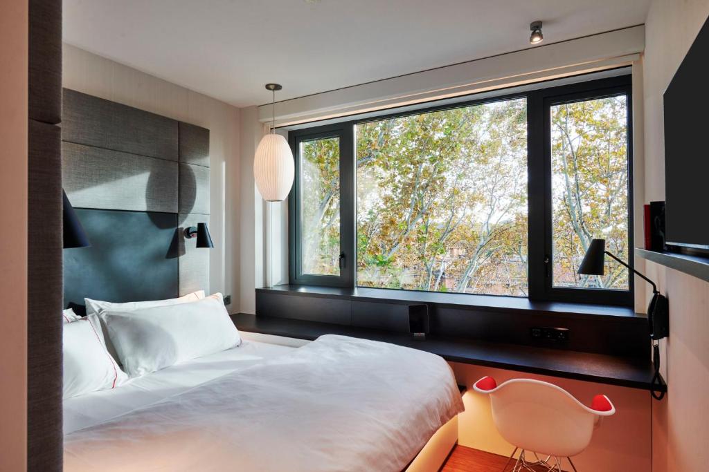 1 dormitorio con cama y ventana grande en citizenM Rome Isola Tiberina en Roma
