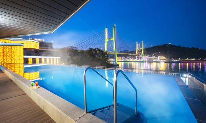 a large swimming pool with a bridge in the background at Yeosu Hotel Haven in Yeosu