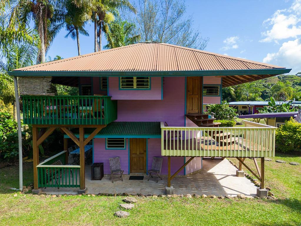 uma casa cor-de-rosa com um telhado e um deque em Heimanarii,slodge Manu em Haapiti