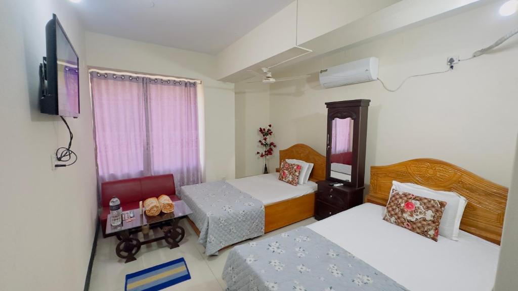 a small room with two beds and a television at Hotel Royal Blue Residence in Dhaka