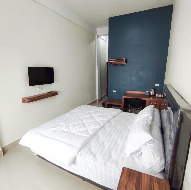 Kala Guest House في Kabanjahe: غرفة نوم بسرير ابيض وتلفزيون بشاشة مسطحة