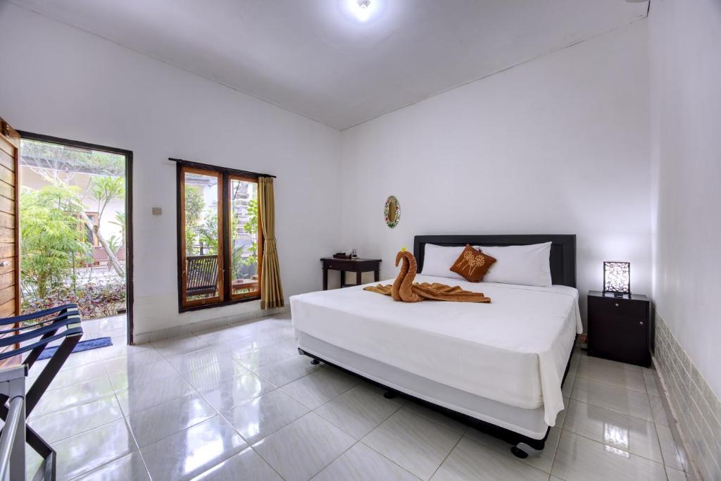 een slaapkamer met een groot wit bed en een raam bij Ari La Casa in Nusa Penida