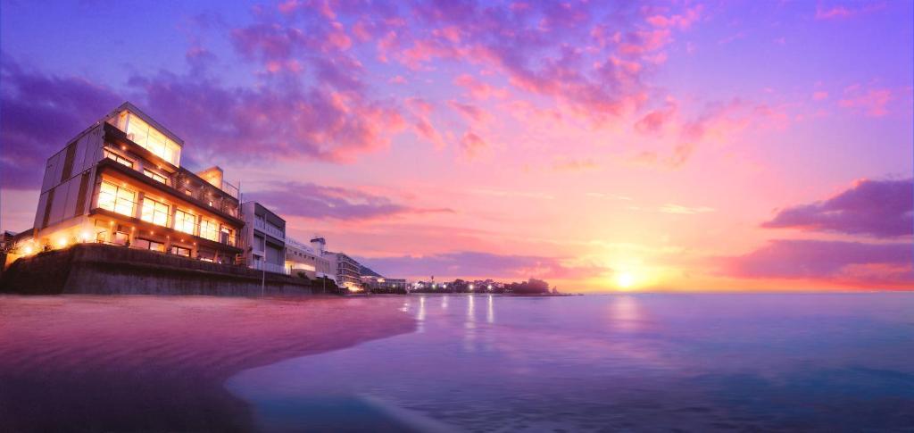 葉山町的住宿－選擇套房酒店，海滩上的建筑,背景是日落