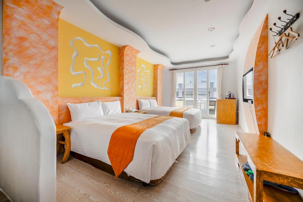 duas camas num quarto de hotel com uma televisão e um quarto em Wei Yuan Hotel em Kenting