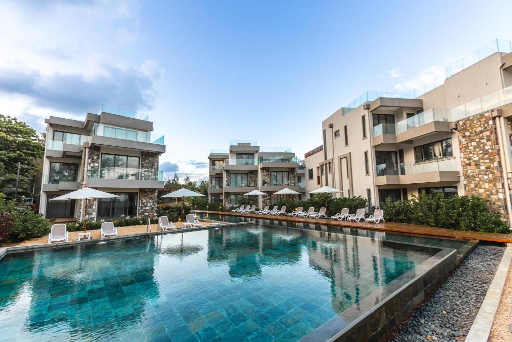 a large swimming pool with chairs and buildings at Brand new, Beachfront Ocean Terraces, Poste Lafayette-Apt-C4 in Poste Lafayette