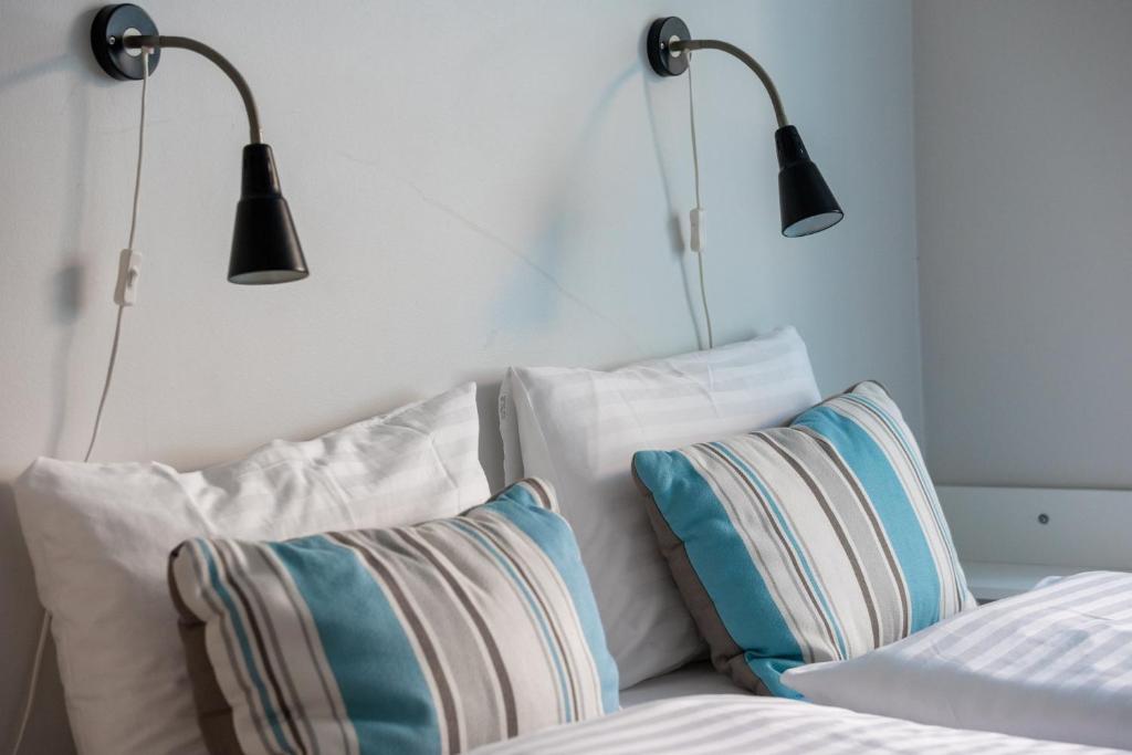 two lights above a bed with white pillows at Hildibrand Apartment Hotel in Neskaupstaður