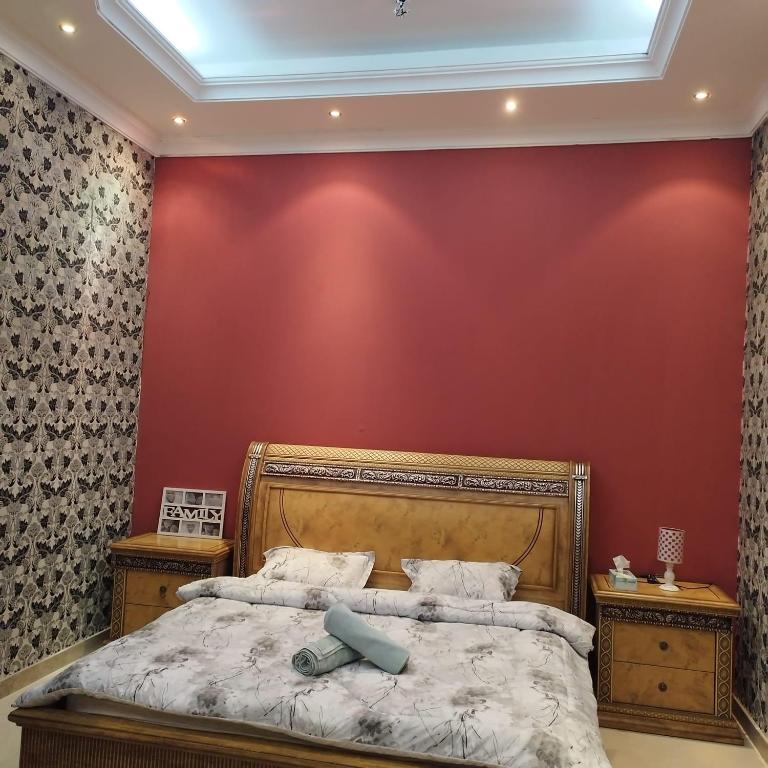 a bedroom with a bed and a red wall at العين الهيلي مصباح بيت14 in Al Ain