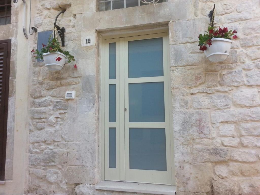 una puerta en el lateral de un edificio de piedra con macetas de flores en VIco Pittore en Modica