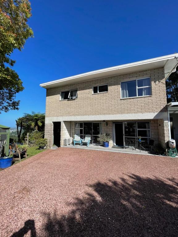 uma casa com uma entrada de cascalho em frente em Swanson-Waitakere Stay in Scenic Sunrise em Auckland