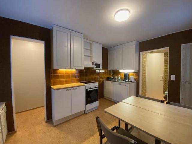 a kitchen with white cabinets and a wooden table and a table and a tableearcher at Apartment HILLI in Rovaniemi