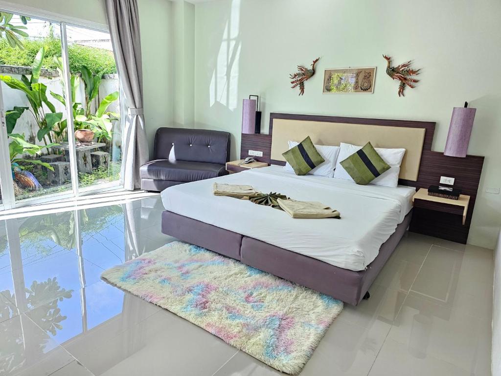 a bedroom with a bed and a chair in it at AM Surin Place - SHA Extra Plus in Surin Beach