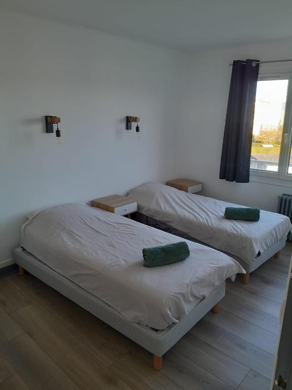 2 Einzelbetten in einem Zimmer mit Fenster in der Unterkunft la Sentinelle in Calais