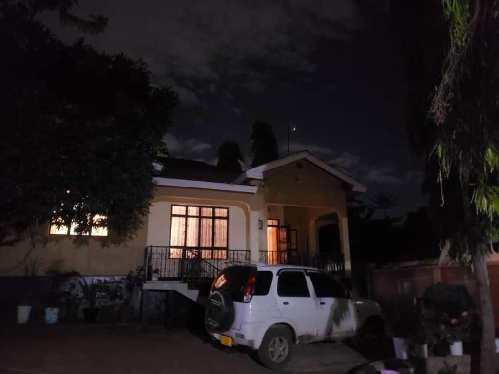 un camion blanc garé devant une maison la nuit dans l'établissement Avacado Homestay, à Arusha