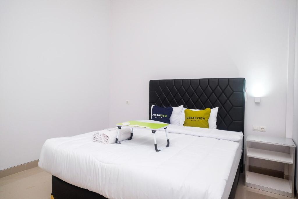- une chambre avec un lit blanc et une tête de lit noire dans l'établissement Urbanview Syariah Loji Arum Stasiun Klaten by RedDoorz, à Klaten