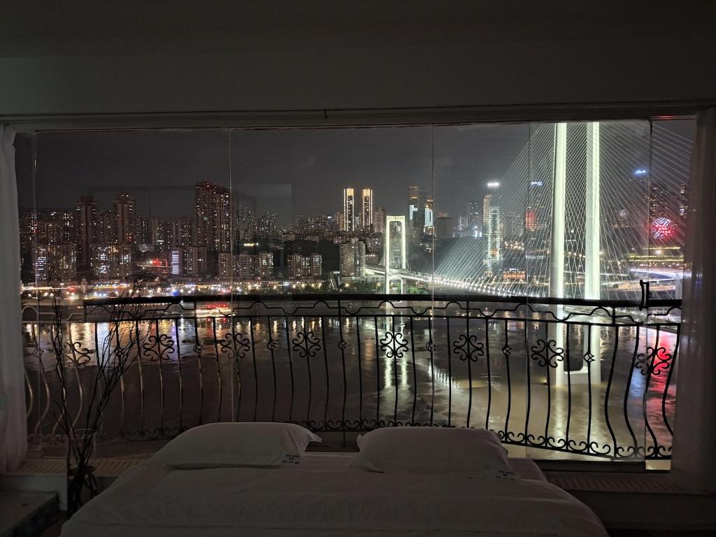 a bedroom with a view of a city at night at Comacros - Chongqing JieFang Cave River View Apartment - Line 1 and Line 2 Jiachangkou Subway Station in Chongqing