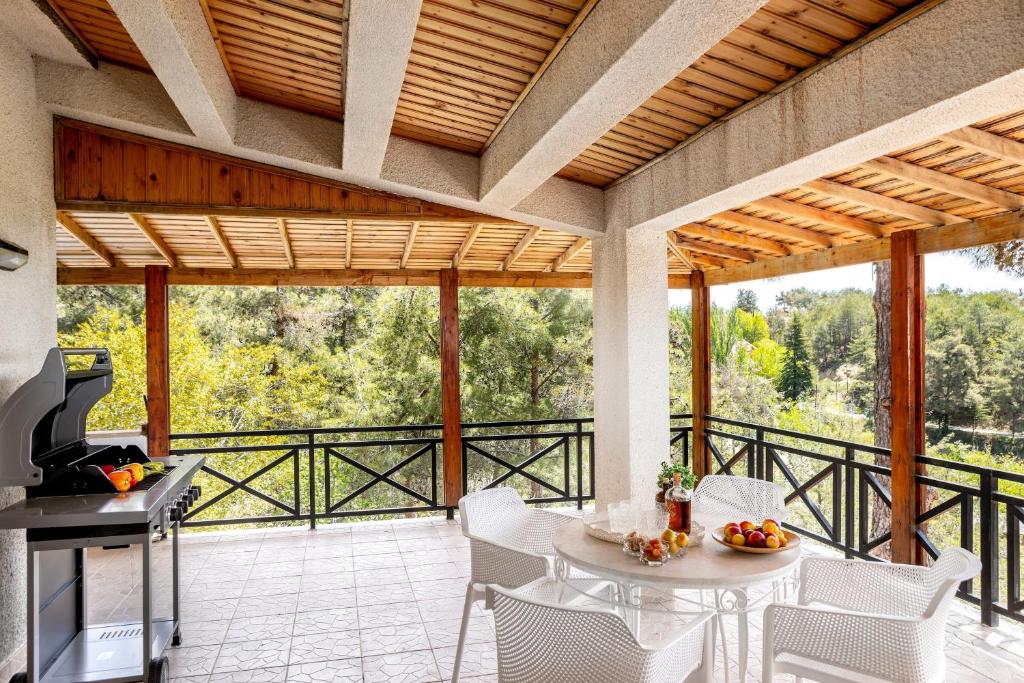 een patio met een tafel en stoelen en een grill bij Platres Forest Panorama Cottage in Platres