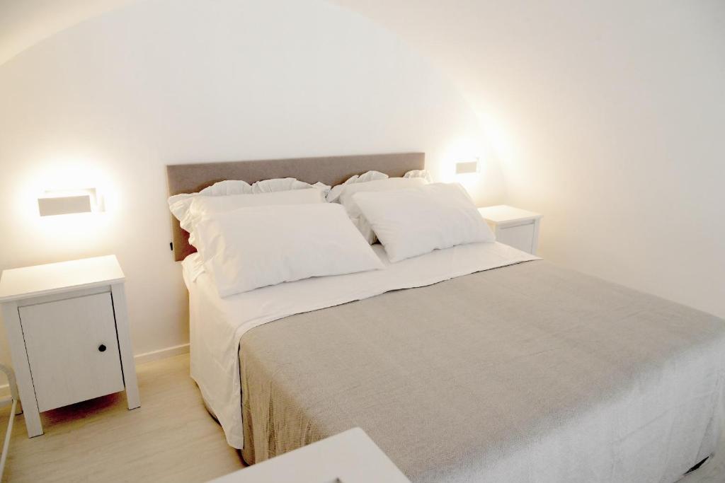 ein weißes Schlafzimmer mit einem großen Bett mit weißen Kissen in der Unterkunft Donna Anna in Polignano a Mare
