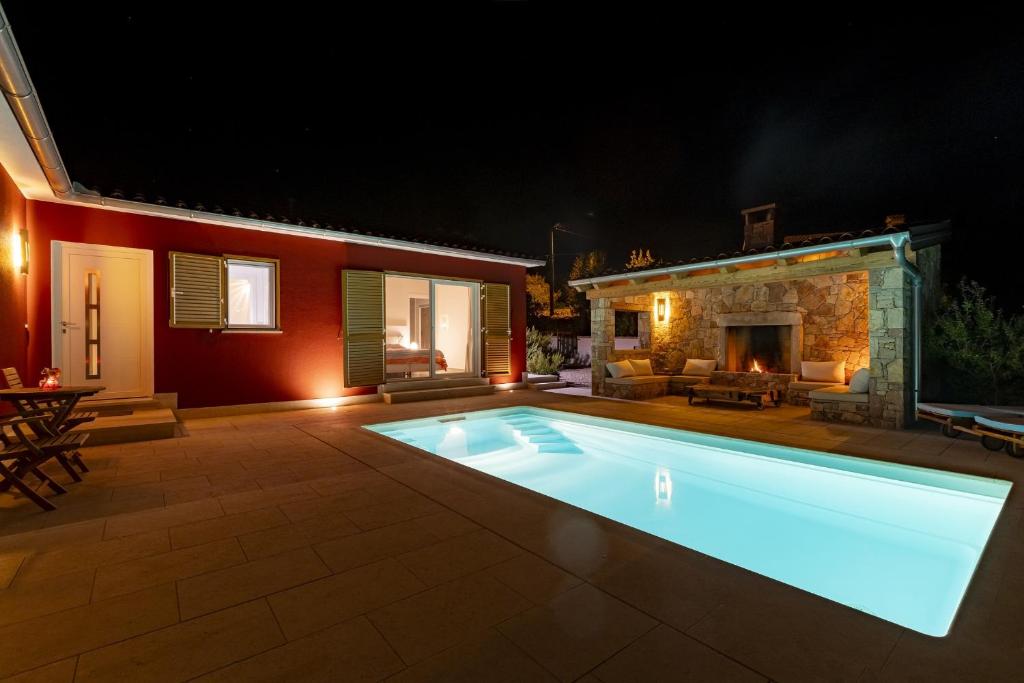 uma piscina em frente a uma casa à noite em Red House Trget with Swimming Pool, Sauna and Jacuzzi em Labin