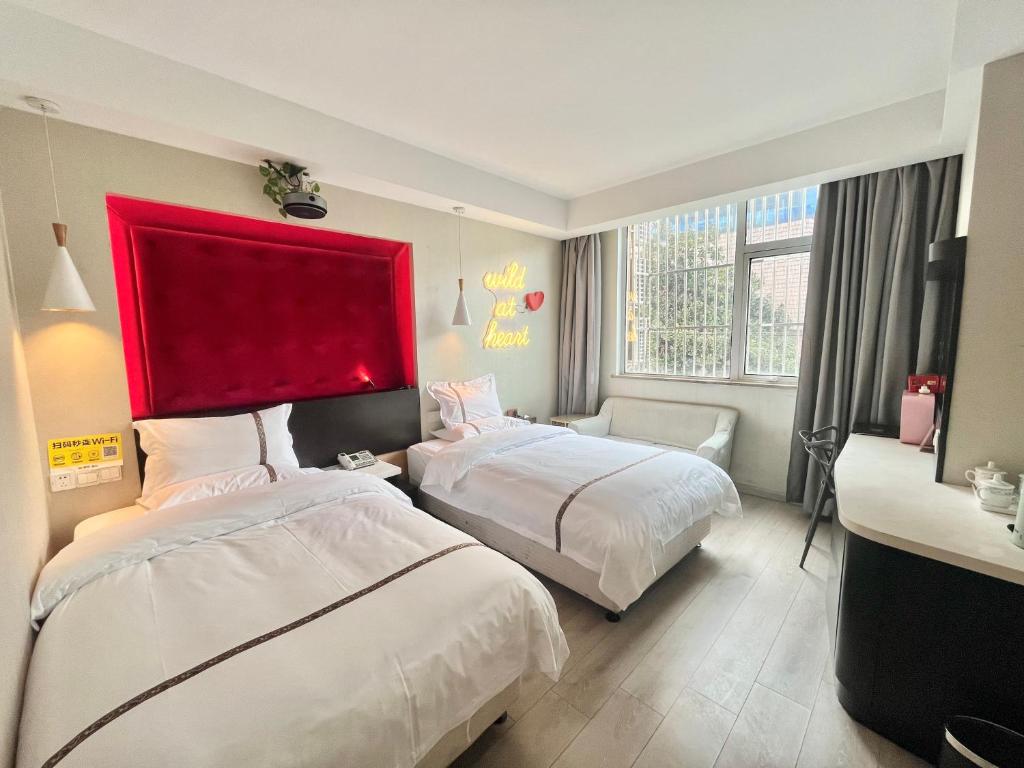a hotel room with two beds and a red headboard at Tianshui Times Hotel Zhangjiagang in Zhangjiagang