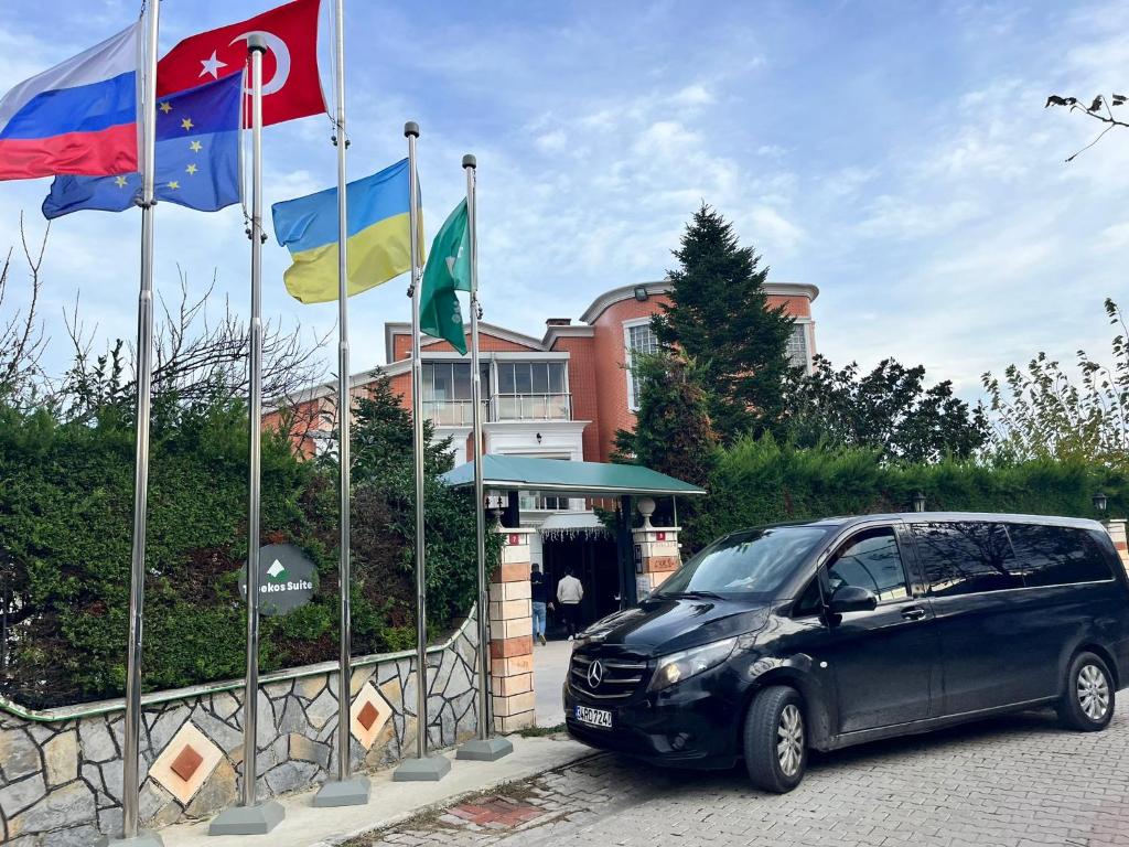 een auto geparkeerd op een parkeerplaats naast de vlaggen bij Treekos Suite Hotel in Arnavutköy