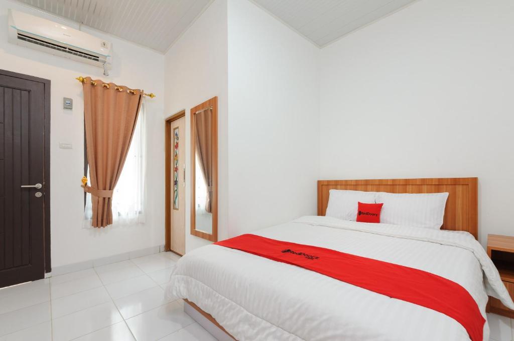 ein Schlafzimmer mit einem großen Bett mit einer roten Decke in der Unterkunft RedDoorz Plus Syariah near Mall Boemi Kedaton Lampung in Kedaton
