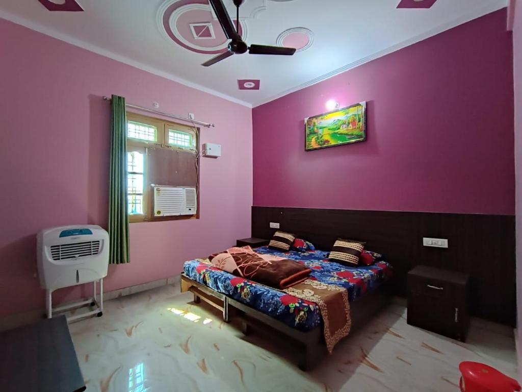 a bedroom with purple walls and a bed with a fan at Ratan Homestay in Shivpuri