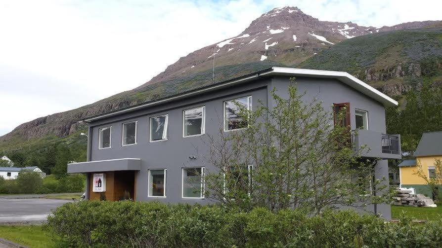 a building with a mountain in the background at Seydisfjördur Guesthouse in Seyðisfjörður