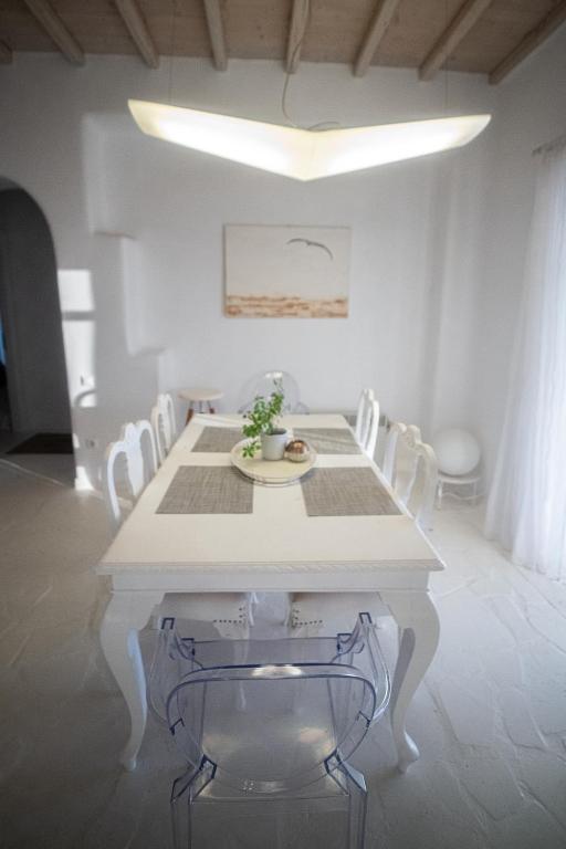 a white dining room with a white table and chairs at White Rock Suites &amp; Villas in Houlakia
