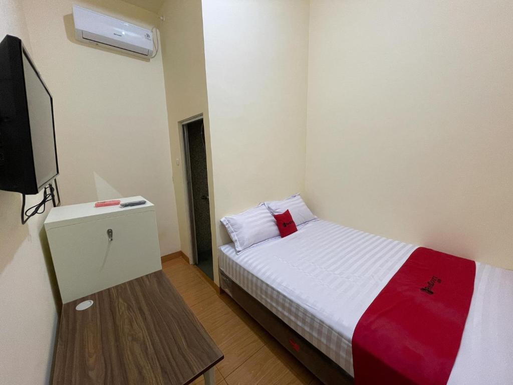 a small room with a bed and a tv at RedDoorz at Ramelau near AP Pettarani in Makassar