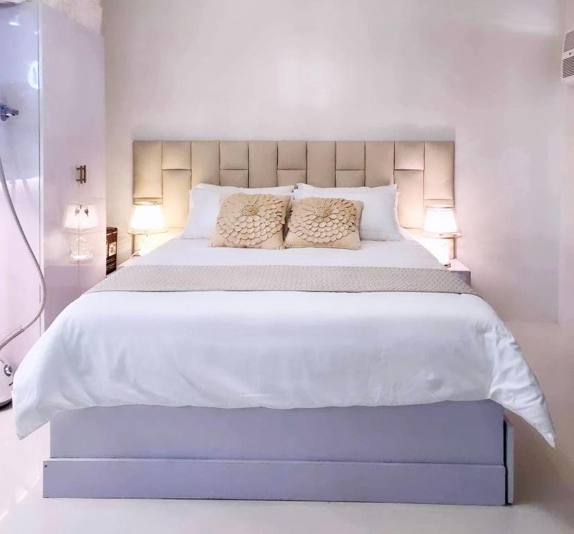 um quarto com uma grande cama branca e 2 almofadas em Cozy Condo Unit in Puerto Princesa City near PPS Airport em Puerto Princesa