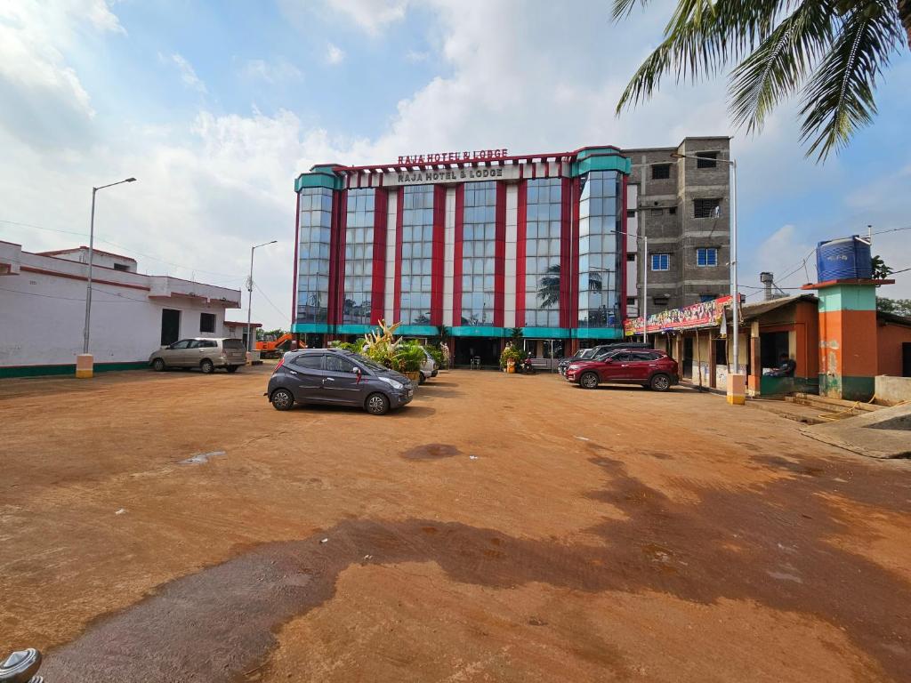 ein großes rotes Gebäude mit Autos auf einem Parkplatz in der Unterkunft Raja Hotel & Lodge - Kharagpur, West Bengal in Shyāmalpur