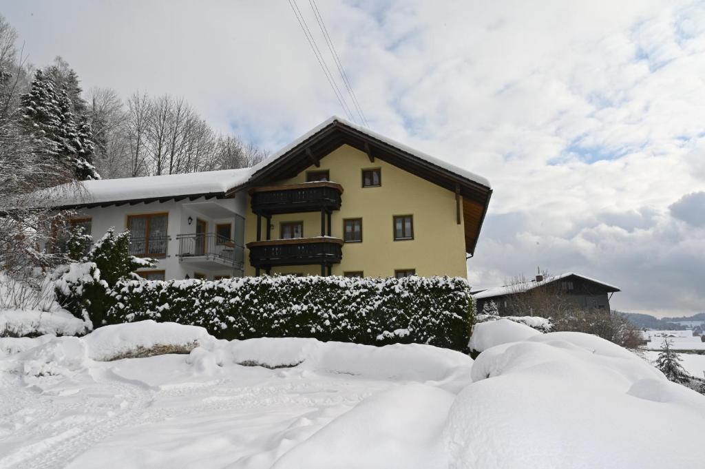 una casa cubierta de nieve delante en Pension Klein, en Bodenmais