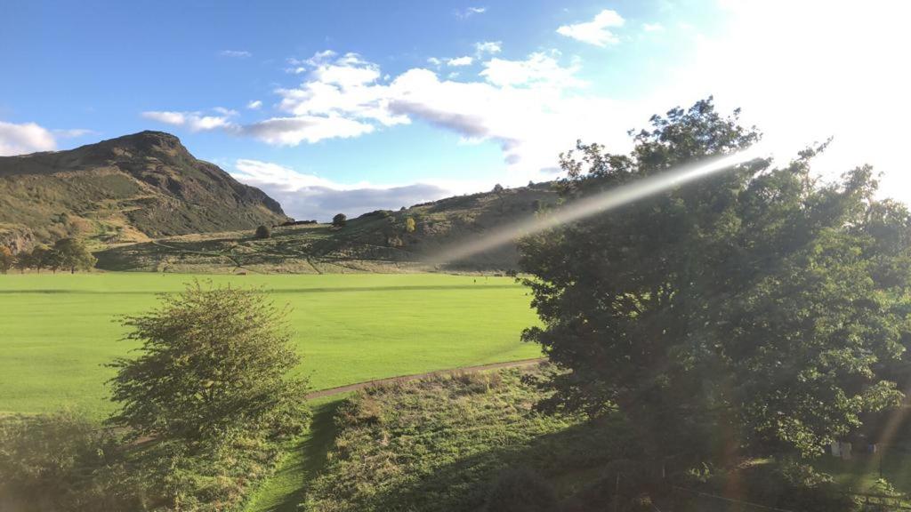 a view of a green field with trees and mountains at Arthur's Seat View in Edinburgh