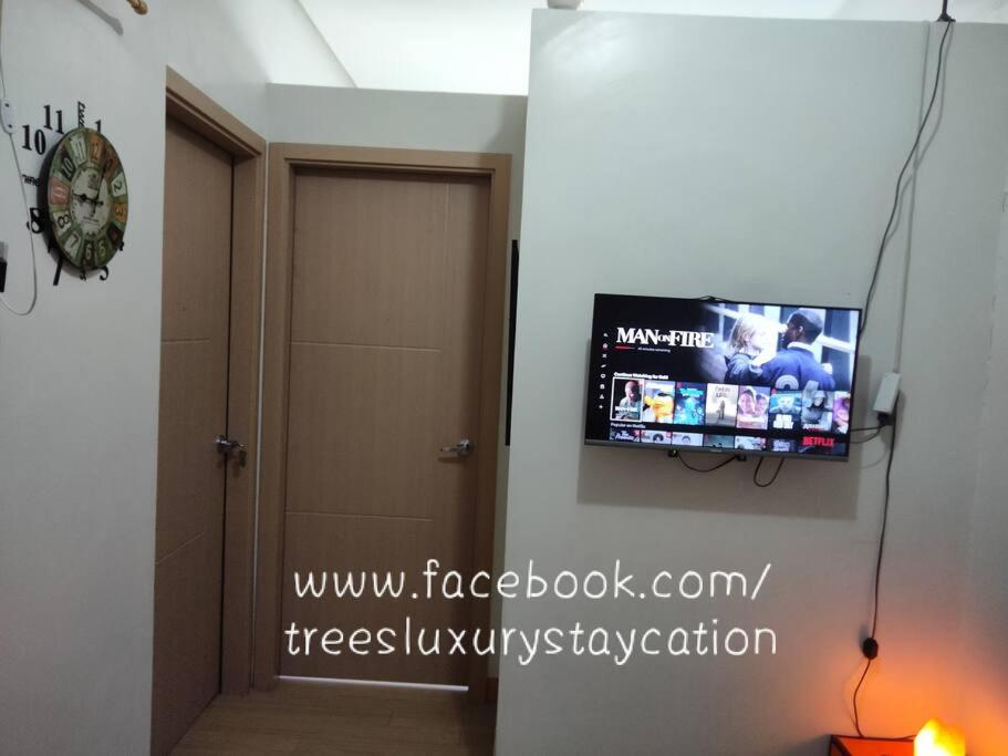 een flatscreen-tv aan een muur naast een deur bij T108F Trees residences Near Sm Fairview in Manilla